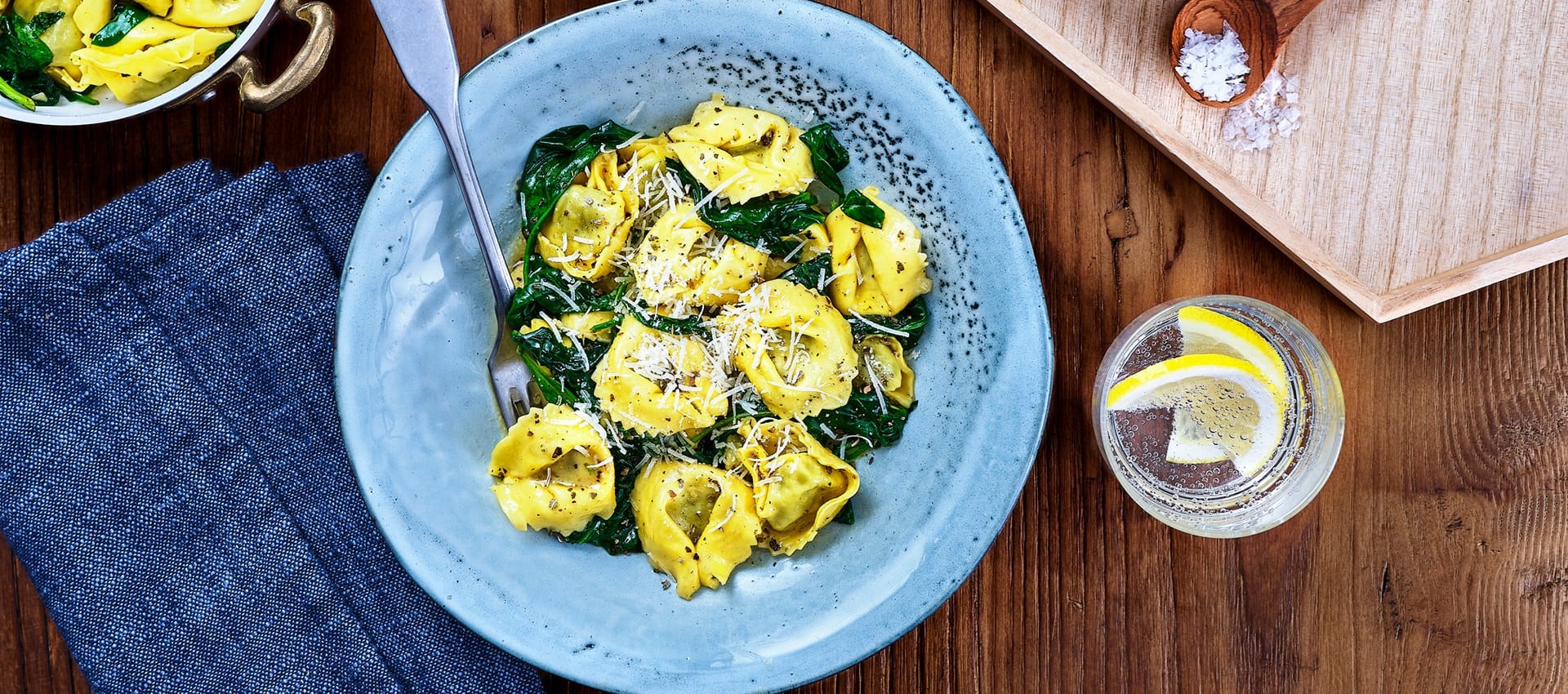 tortellini med salvia och spenat upplagd på blå tallrig