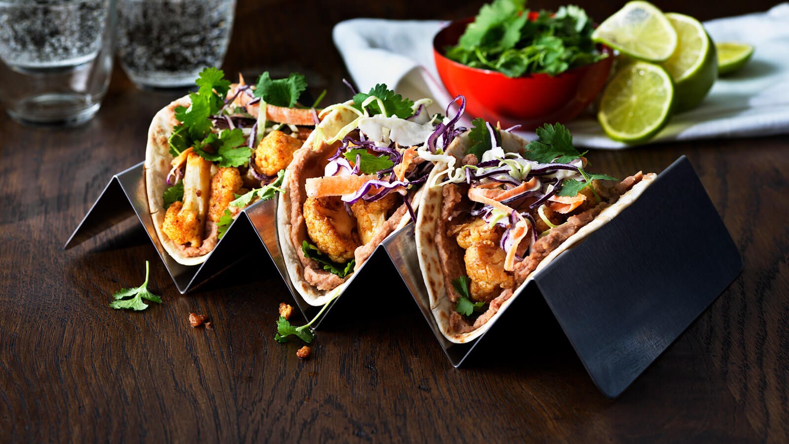 Three cauliflower tacos served on a stand