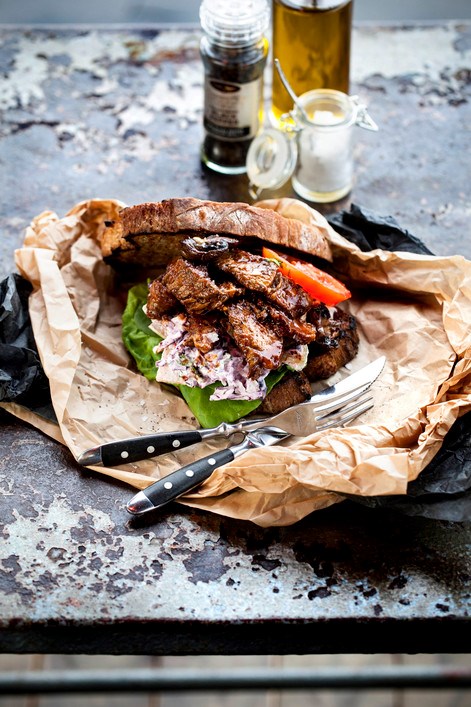 Brisket rundvlees op een warm broodje met groenten en sla op een bord