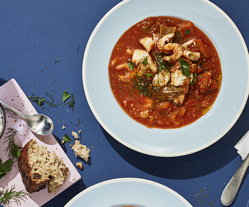  Fiskesuppe servert på bord med brød, vann og tilbehør