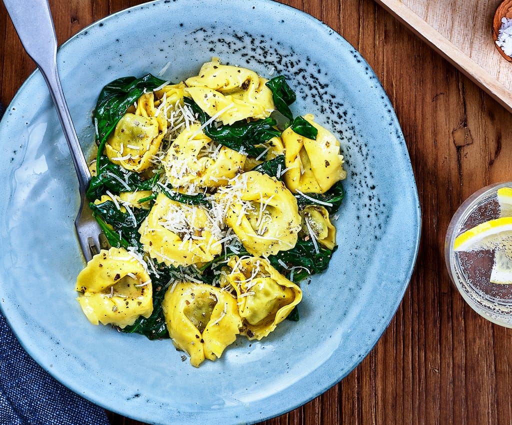 tortellini med salvia och spenat upplagd på blå tallrig