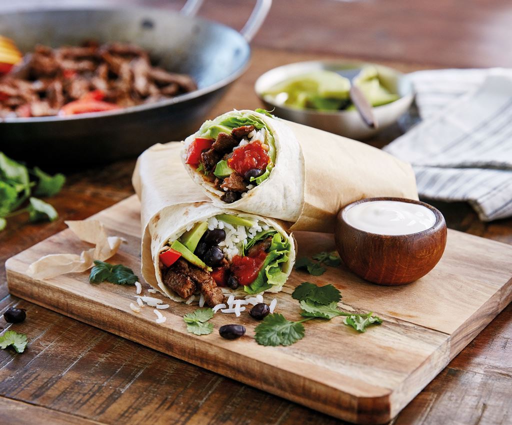 2 halve beef burrito's gevuld met rundvlees, rijst en groenten op een plankje