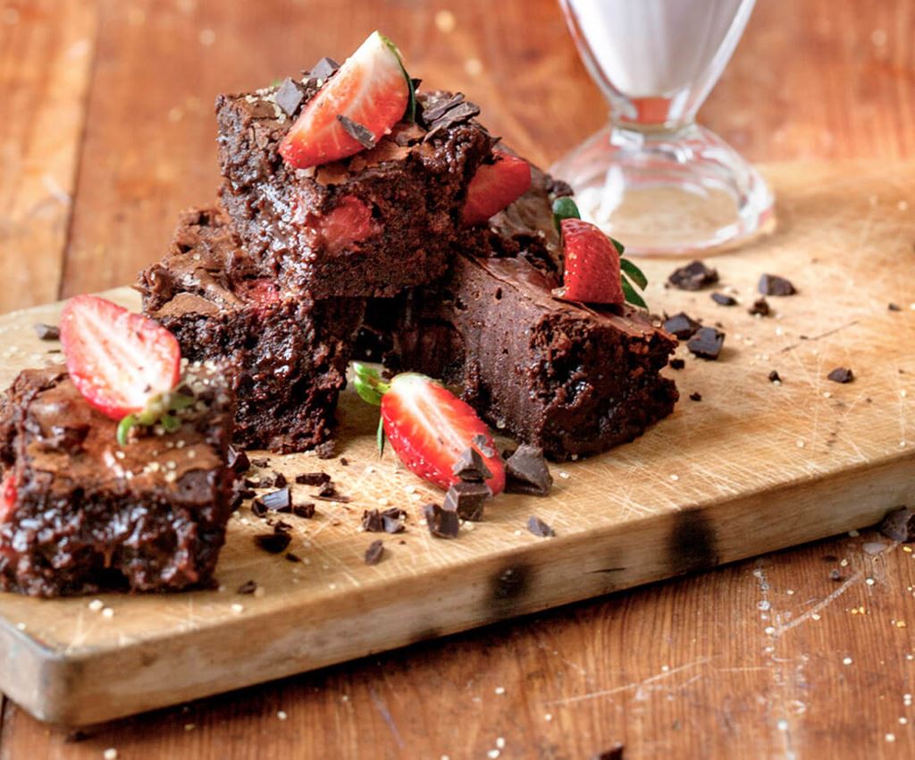 Chocolate brownies with straberries on a wooden board