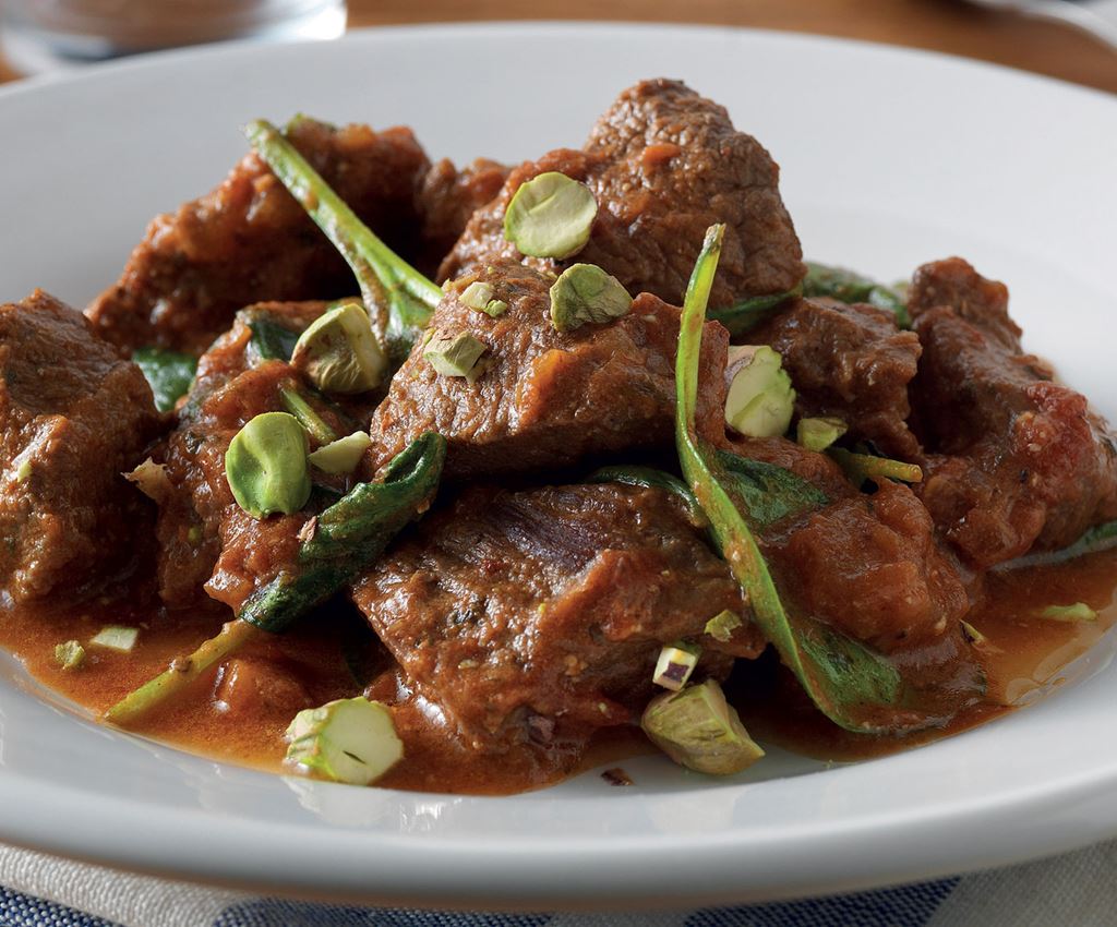 Viande d'agneau cuite à l'étuvée dans un mélange d'épices, accompagnée d'épinards entiers et de pistaches